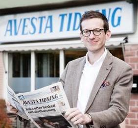 Gabriel Ehrling står stolt framför Avesta tidningslokaler med en rykande färsk kopia av dagens Avesta tidning. Unga man i tweedkavaj, glasögon och ett brett leende